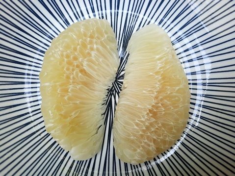 Peeled Pomelo fruit on plate.