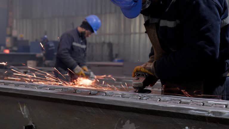 Metal workers using a grinder