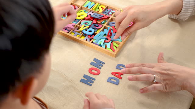 Asian happy single mother and son playing alphabet games with plastic toys, mom helping child learn foreign language for improve mental health and memory. family spending time together in holiday.