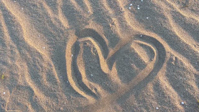 Write a heart in the sand.