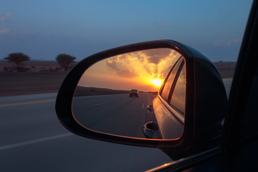 Shot on the highway with the sunset reflected in the car mirror