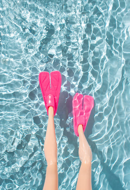 Woman legs with pink fins for snorkeling in water. Minimal summer beach vacation concept. Woman legs with pink fins for snorkeling in water. Minimal summer beach vacation concept. diving flippers stock pictures, royalty-free photos & images