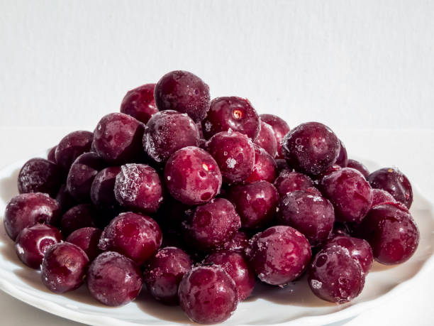 istock Frozen sweet, ripe cherry berries covered with hoarfrost on white plate with white background in bright sunlight 1462018557