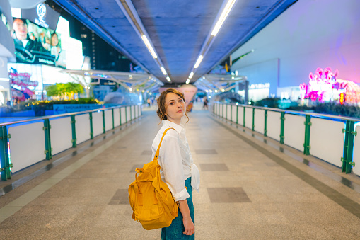 Young Caucasian woman in white shirt walking in Bangkok at night