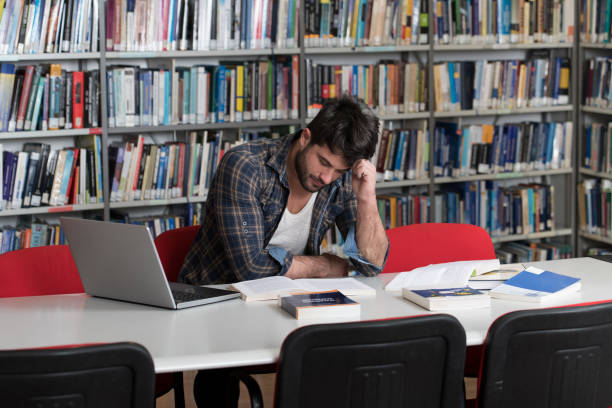 istock Confused Male Student Reading Many Books for Exam 1462023789
