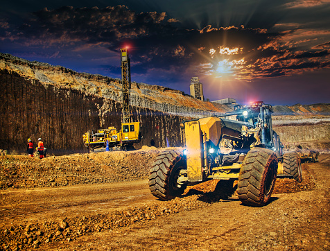 african workers using a grader and a drilling machine in a diamond mine at sunset