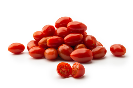 High angle view of Heap of fresh small red sweet snack tomatoes on white background. Focus on foreground.