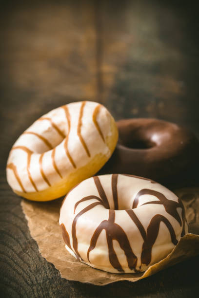 istock White and dark chocolate donuts on a dark wooden table, vertical with copy space 1462034458