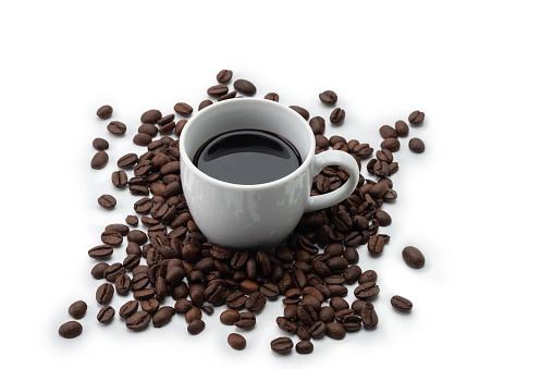 Cup of coffee with roasted coffee beans against a white background, high angle view.