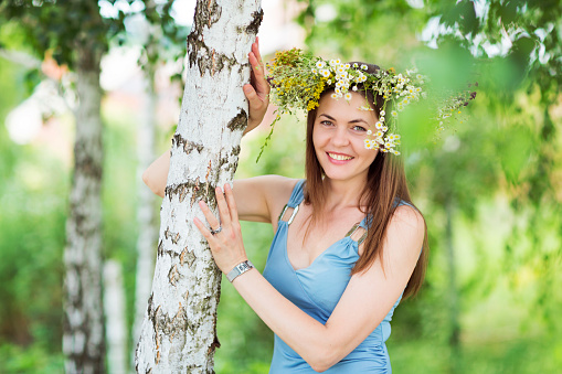 Pretty young woman with a flower wreath on her head in a forest
