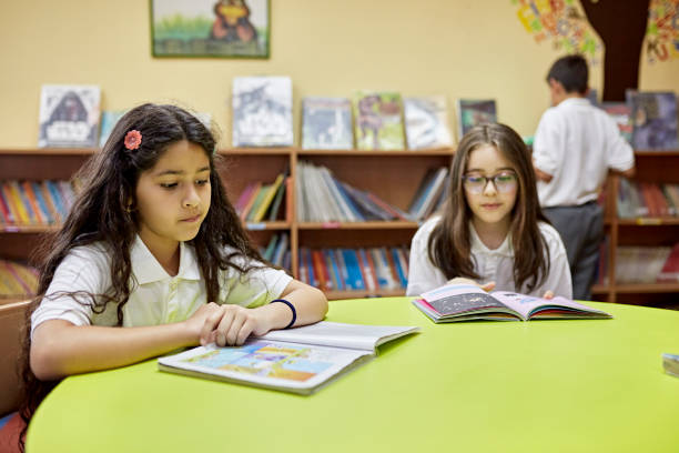 istock Young girls reading in school library 1462051482