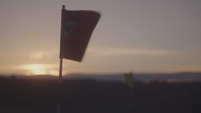Close-up shot of a waving golf flag during a sunset