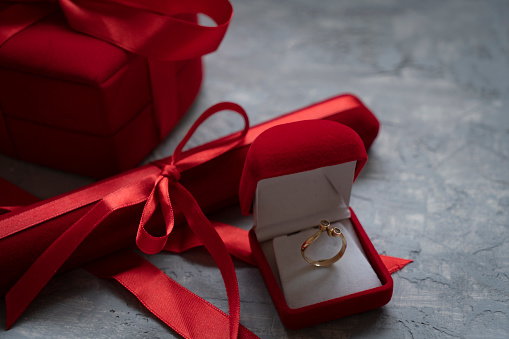 Concept of proposal, wedding, love, Valentine's Day. Gold wedding ring in a gift box surrounded by flowers. Close-up.