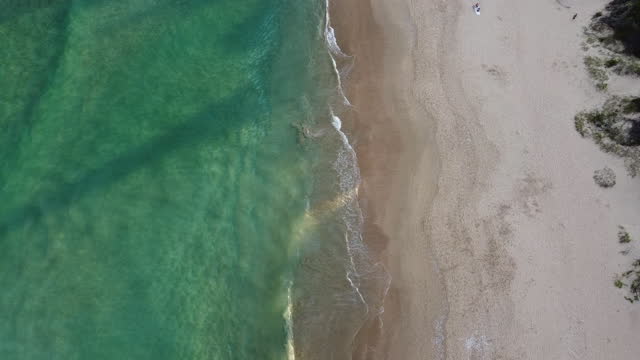 Aerial shot from above of waves on empty South African beach shoreline.