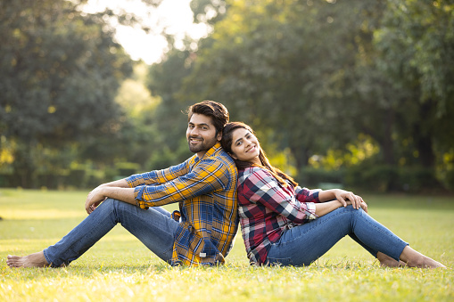 Young couple sitting back to back in park