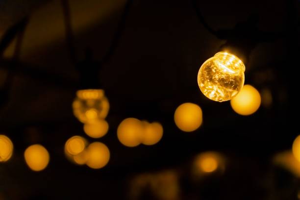 istock Selective focus shot of a small light bulb with yellow light with bokeh background 1462064276