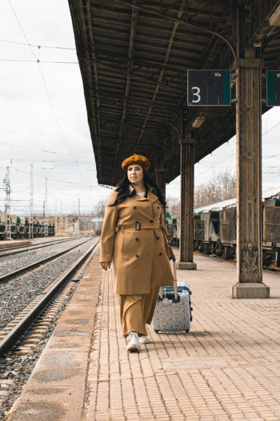 istock Fat woman with suitcase waiting for the train on the platform 1462083818