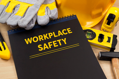 Workplace safety manual with construction equipment on wooden table