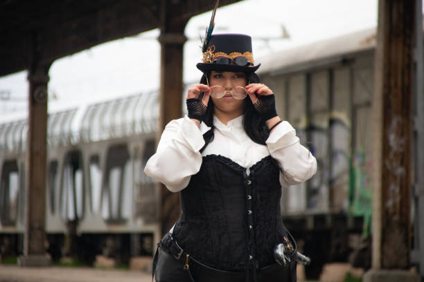 istock Thick woman dressed in steampunk style in an abandoned train station. Train car with graffiti on the back of it. 1462085608
