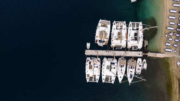 Beautiful coast with marina and small harbor on Mediterranean sea and anchored sailboats and catamaran. Island of Meganisi, Greece.