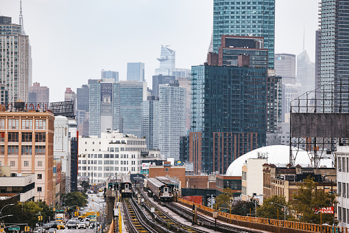 Modern cityscape of Midtown Manhattan on the background while a train of the NYC Subway passing by in the Queens