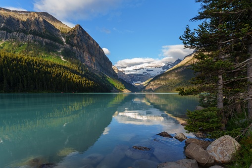 The stunning mountain setting of Lake Louise with the reflection of the soaring peaks in the turquoise waters in Canada