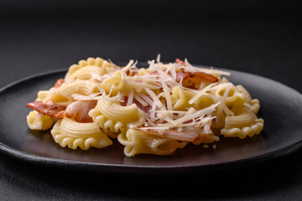 istock Delicious pasta with bacon and parmesan cheese on a black ceramic plate 1462107281