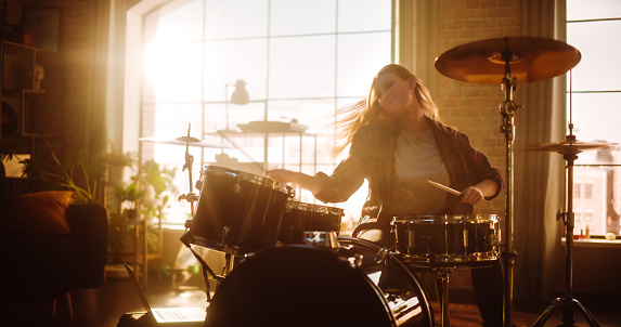 Portrait of a Beautiful Young Drummer Playing at a Band Rehearsal, Doing Tricks with Drumsticks. Learning Drum Solo on Drums and Cymbals in Living Room of Stylish, Spacious Loft Apartment.