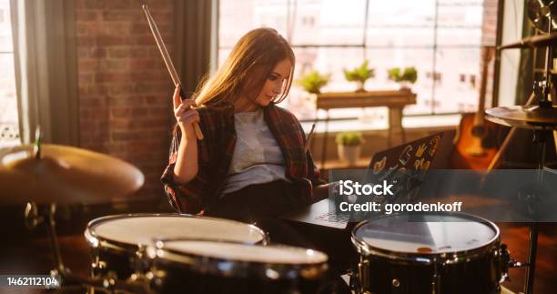 Young Musician Taking A Breather Resting Between Intense Drum Solos Alternative Stylish Female Using Laptop Computer Checking Social Media Chatting With Friends Loft Living Room On A Sunny Day Stock Photo - Download Image Now