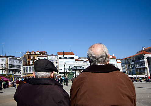 Betanzos, Spain_March 6, 2011: Street view, rear view of two senior men talking, town square in Betanzos, A Coruña province, Galicia, Spain.