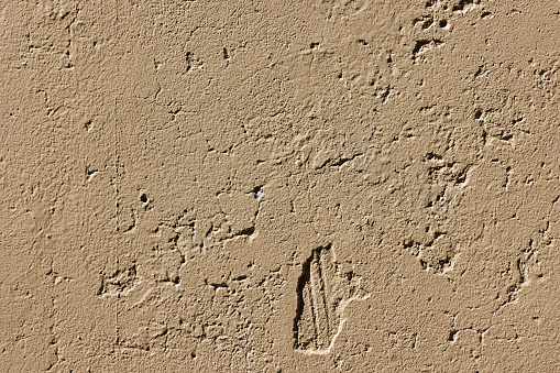Part of a textured beige concrete wall.