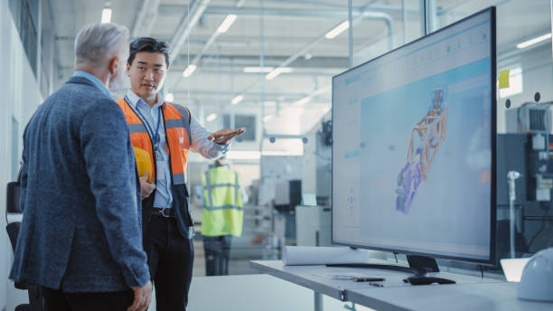 Factory Office Meeting: Rack Focus from Worker to Engineer Talking with Business Partner in Conference Room with TV Display. Colleagues Discussing Modern Hydraulics Mechanism for Industry Equipment.