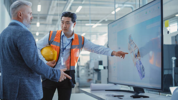 reunión de la oficina de la fábrica: gerente senior hablando con el ingeniero en una sala de conferencias con televisor. empleados de la industria pesada discutiendo el mecanismo hidráulico moderno para equipos de la industria. - drafter fotografías e imágenes de stock