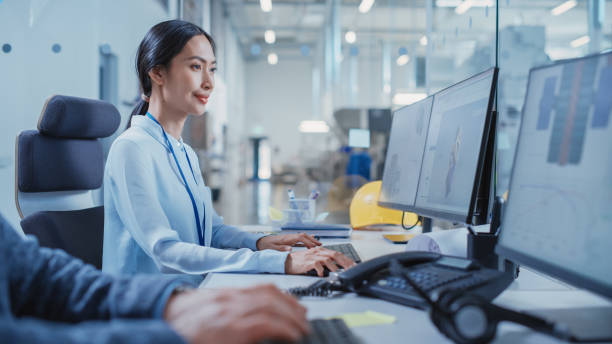 istock Factory Office Room: Industrial Engineers Developing Models of a Heavy Industry Machine Parts on a Computer 3D Software. Modern Technological Industry 4.0 Research and Development Center. 1462131088