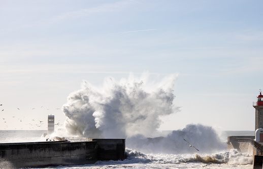 Big wave crashing over the wall at Farolim da Barra do Douro lighthouse in Porto, Portugal