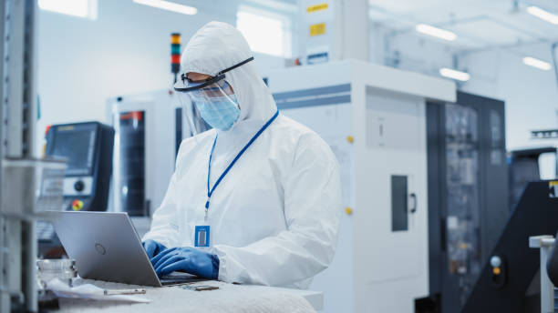 istock Modern Technology Concept: Engineer in Coverall Working on Laptop Computer, Examining a Circuit Board with Microchips and Typing Data. Technician Testing New Electrical Equipment. 1462133541