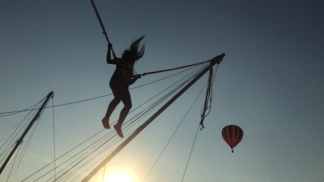 Silhouette of a young girl jumping on a bungee trampoline