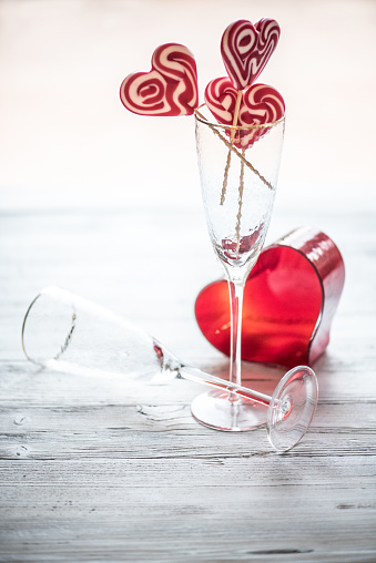 Heart Shape Lollipops in Champagne Flute on White Wooden Background, Valentine´s Day Concept