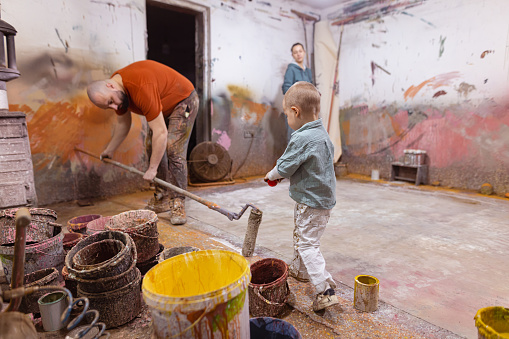 Lovely photography of a painter man and his wife and son, working together in their workshop. Family business concept.