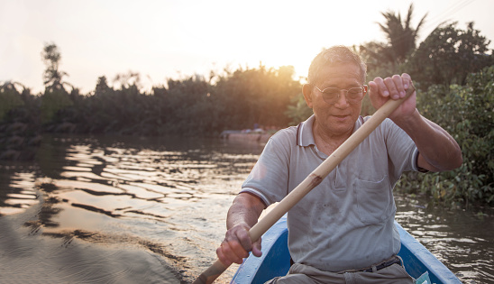 senior old asian man roll boat in the river in long life active outdoor activity concept