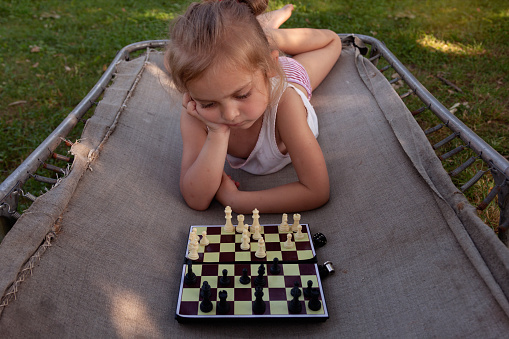 Child  propping her head while planning her next chess move