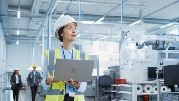 istock A Happy and Smiling Asian Female Engineer in White Hard Hat Standing with Laptop Computer at Electronic Manufacturing Factory. Successful Employee Watching the Work Flow 1462146426