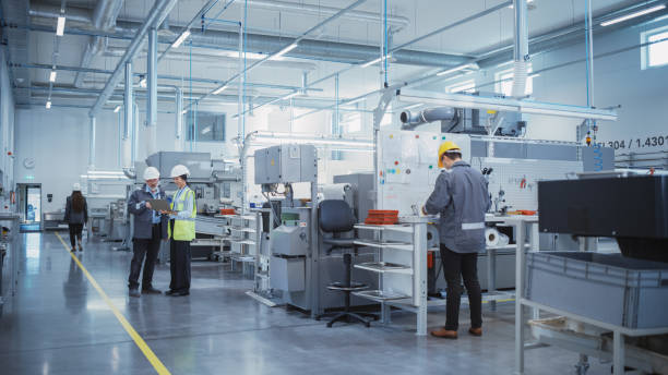 istock Industrial Factory: Team of Engineers, Technicians and Workers, Working on Production Plant, Developing CNC Parts, Programming Machines. Two Specialists Discussing Project Plan and Using Laptop. 1462146852