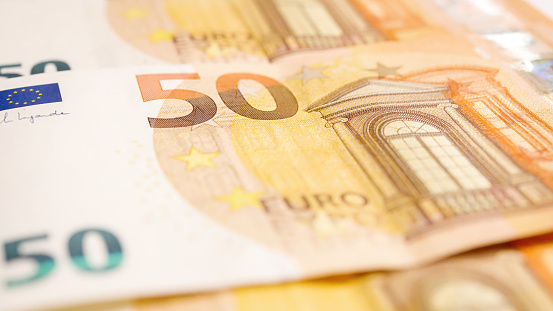 Macro shot of a European Union banknote of 50 EUR, close-up of the number fifty, isolated on a white background, selective focus.