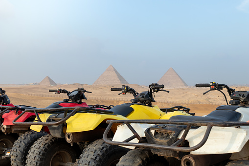 Colorful parked quad bikes ATV safari in desert with pyramids in background Cairo, Egypt. No people