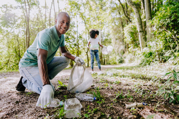 hombre maduro recogiendo basura en la naturaleza - conservacionista fotografías e imágenes de stock