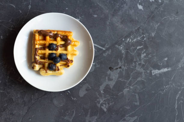 istock Waffle with chocolate paste and blueberries on a white plate. Gray background. View from above. 1462152854