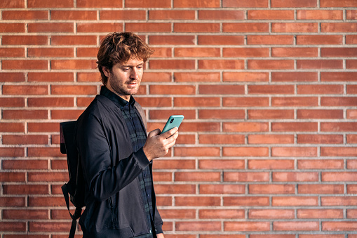 Stock photo of handsome man using his cellphone in the street.