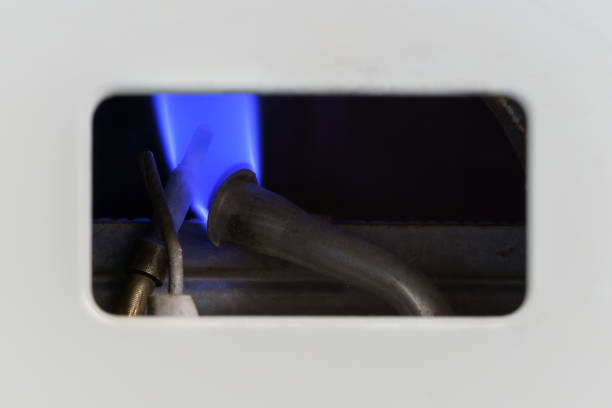 Pilot light auto igniter inside a hot water heater with flames stock photo