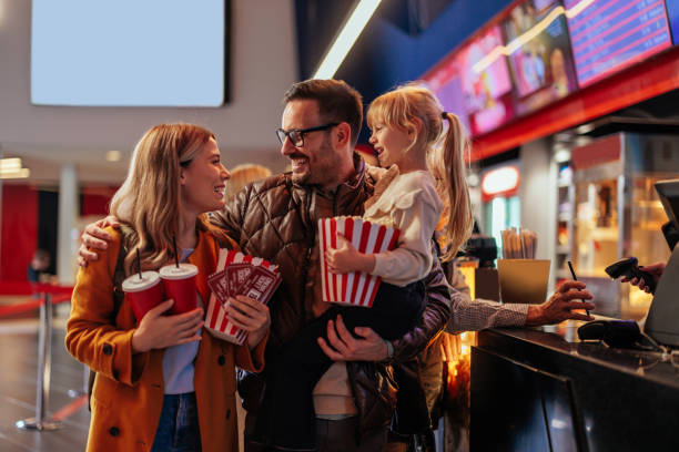 Cheerful parents with child in movie theater. stock photo